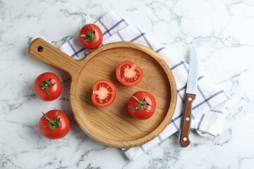 Wooden cutting board, tomatoes and knife on white marble table, flat lay