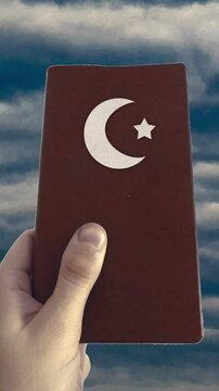 Hand holding islamic book and cloudscape at background 2d looped animated video
