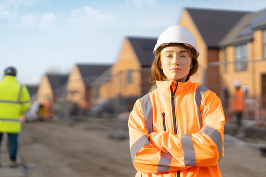 Young woman construction worker stands confidently at building site