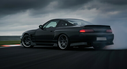 Obraz premium Black sports car drifting on race track under overcast skies