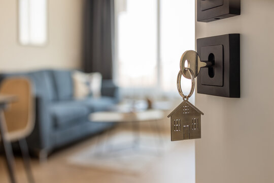 Open door to a new home with key and home shaped keychain. Mortgage, investment, real estate, property and new home concept