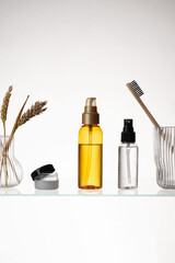 Fototapeta premium Different cosmetic products on a glass shelf on white background. Mockup of skincare and bath products on a glass shelf
