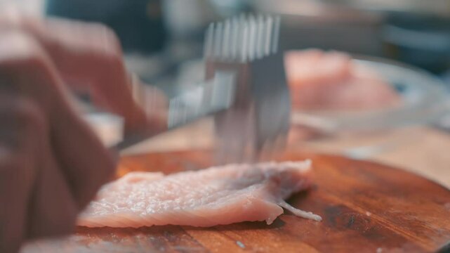 Meat Tenderizer Hammering Turkey Fillet - Close Up of Tenderizing Raw Poultry on Wooden Cutting Board in Kitchen
