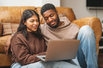 Couple enjoys quality time together while browsing on laptop in  cozy living room during a relaxing...