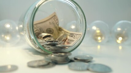 50 dollar banknote in a transparent glass jar. Coins and paper money. Cash and Moneybox concept. Silver colored coins.	
