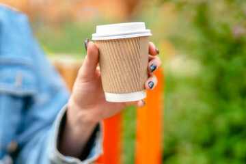 Warm beverage is held in hand outdoors while sitting on bench in vibrant garden during a sunny afternoon