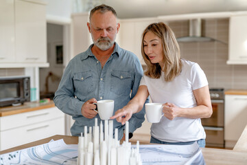 Fototapeta premium Couple discussing design project in modern kitchen while enjoying coffee in the morning light