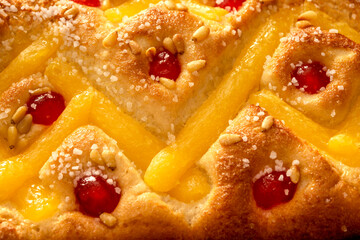 Macro shot of the surface of a "Coca de Sant Joan" with cream, candied cherries, and pine nuts, a festive Catalan sweet typical of the Saint John's Eve celebration, captured in a close-up top view