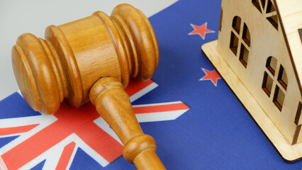 Law and real estate business in New Zealand. Gavel with wooden house on New Zealander flag.