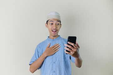 Asian Muslim man holding smartphone with facial expression