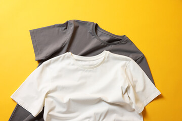 Blank t-shirts on yellow background, flat lay. Mockup for design
