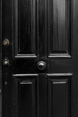 Elegant black wooden door with vintage knob and detailed paneling