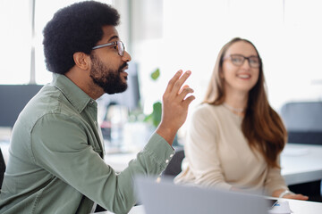 Fototapeta premium Smiling young professional confidently working in a creative office environment. Engaged in a collaborative discussion with a diverse team, bringing fresh ideas to the table.