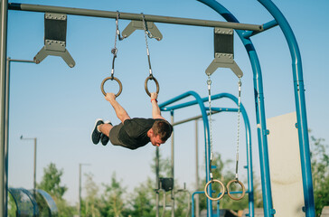 Perfectly parallel to the ground, a man confidently executes an iron cross on rings in a bright...