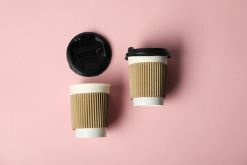 Paper cups with lids on pink background, flat lay. Mockup for design