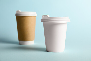 Paper cups on light blue background, selective focus. Mockup for design