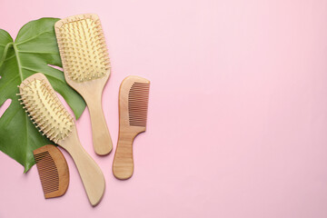 Wooden hair brushes, combs and monstera leaf on pink background, flat lay. Space for text