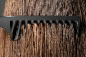 Brushing hair with plastic comb, closeup view