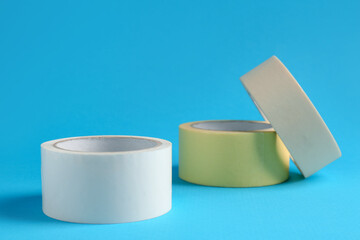 Rolls of different adhesive tapes on light blue background