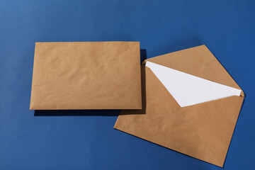 Kraft paper envelopes with letter on blue background, top view. Mockup for design