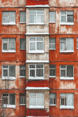 Obraz premium Weathered red apartment building with snow-covered windows in urban setting