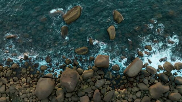 Imagem aerea aberta das &aacute;guas do mar batendo nas pedras da costa