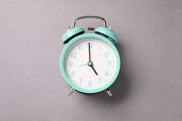 One turquoise alarm clock on light grey background, top view