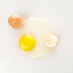 Isolated in White Background, a Raw Egg With a Bright Yolk Surrounded by Broken Eggshells