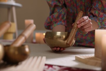 Woman with singing bowls and burning candles indoors, closeup