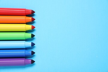 Many colorful markers on light blue background, flat lay. Space for text