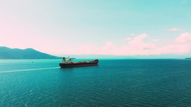 Imagem aerea orbitando sobre navio que passa pr&oacute;ximo a costa em praia 