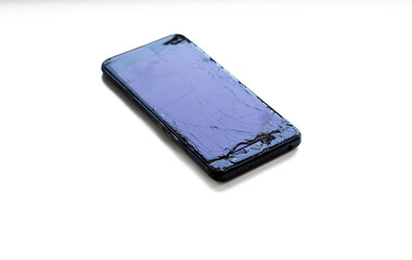 Broken smartphone with severely cracked screen on white background. 