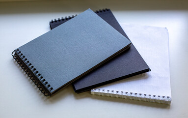 Spiral-bound sketchbooks stacked on a white surface. 