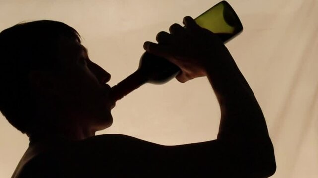 silhueta de homem bebendo vinho em garrafa