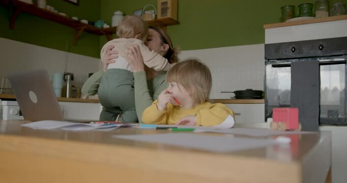 Mother multitasking with kids at home workspace