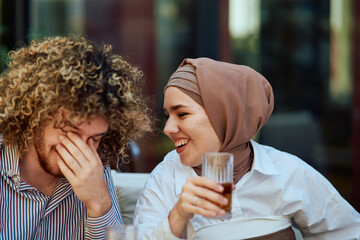 A Muslim Woman in a Hijab Enjoying a Juice and Conversation with Her Friend at a Coffee.