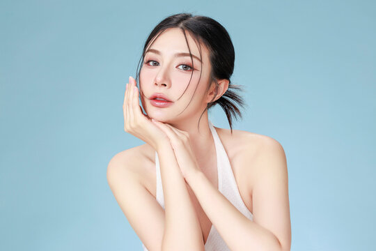 Beautiful young Asian woman model bun hair with natural makeup on face clean fresh skin on isolated blue background. Cute girl portrait, Facial treatment, Body care, Beauty and Spa.