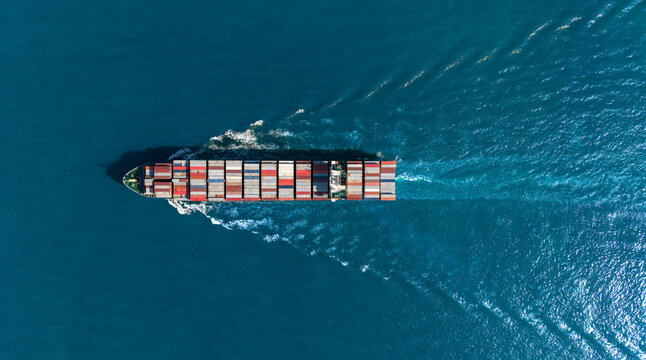 Top view Cargo Container ship with contrail in the ocean ship carrying container and running for import export concept technology freight shipping by ship. - Powered by Adobe