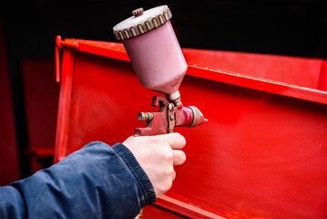 Rebuilding upgrading and modifying trailer. Man painting a metal trailer with spray gun.
