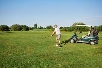 Golfer using a prosthetic leg takes a shot on a beautiful day while enjoying the grassy fairway and...