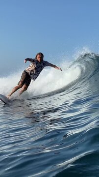 Vertical video of a long-haired male surfer surfing in the Indian Ocean.Wide angle shot.Slow motion video