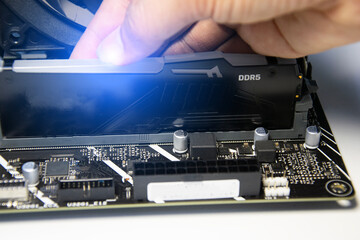 The technician is installing DDR5 RAM onto the motherboard.