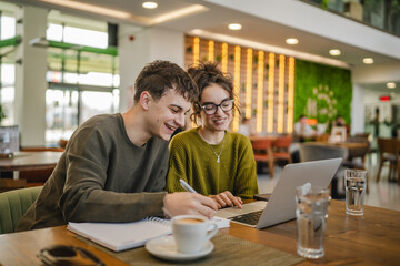 young couple work together and learn on laptop at cafe