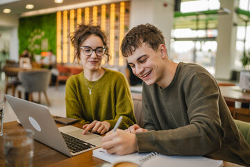 young couple work together and learn on laptop at cafe