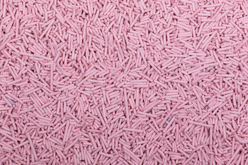 Close-up of uncooked pink vermicelli pasta, small cylindrical noodles scattered in a textured background. Detailed food texture ideal for culinary, packaging, and ingredient concepts.