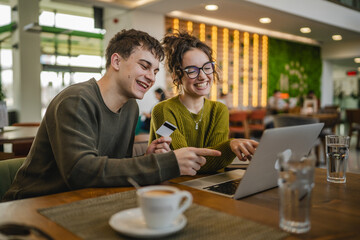 young happy couple use credit card for online shopping on laptop