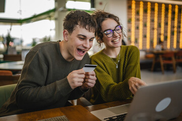 young happy couple use credit card for online shopping on laptop