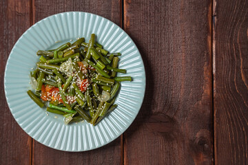 Tzimmes with green beans and tomatoes sprinkled with sesame seeds Jewish dish in a plate