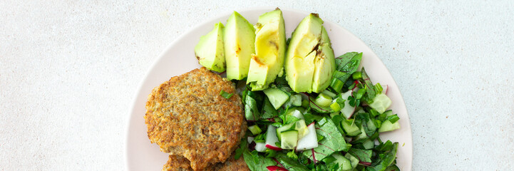 Quinoa cutlets and mixed salad with avocado and radishes, kiwi and water with lemon, delicious hearty breakfasts, vegan lunch plate banner