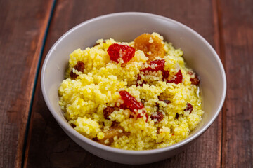 Steamed couscous with dogwood, nuts and raisins in a plate on the table